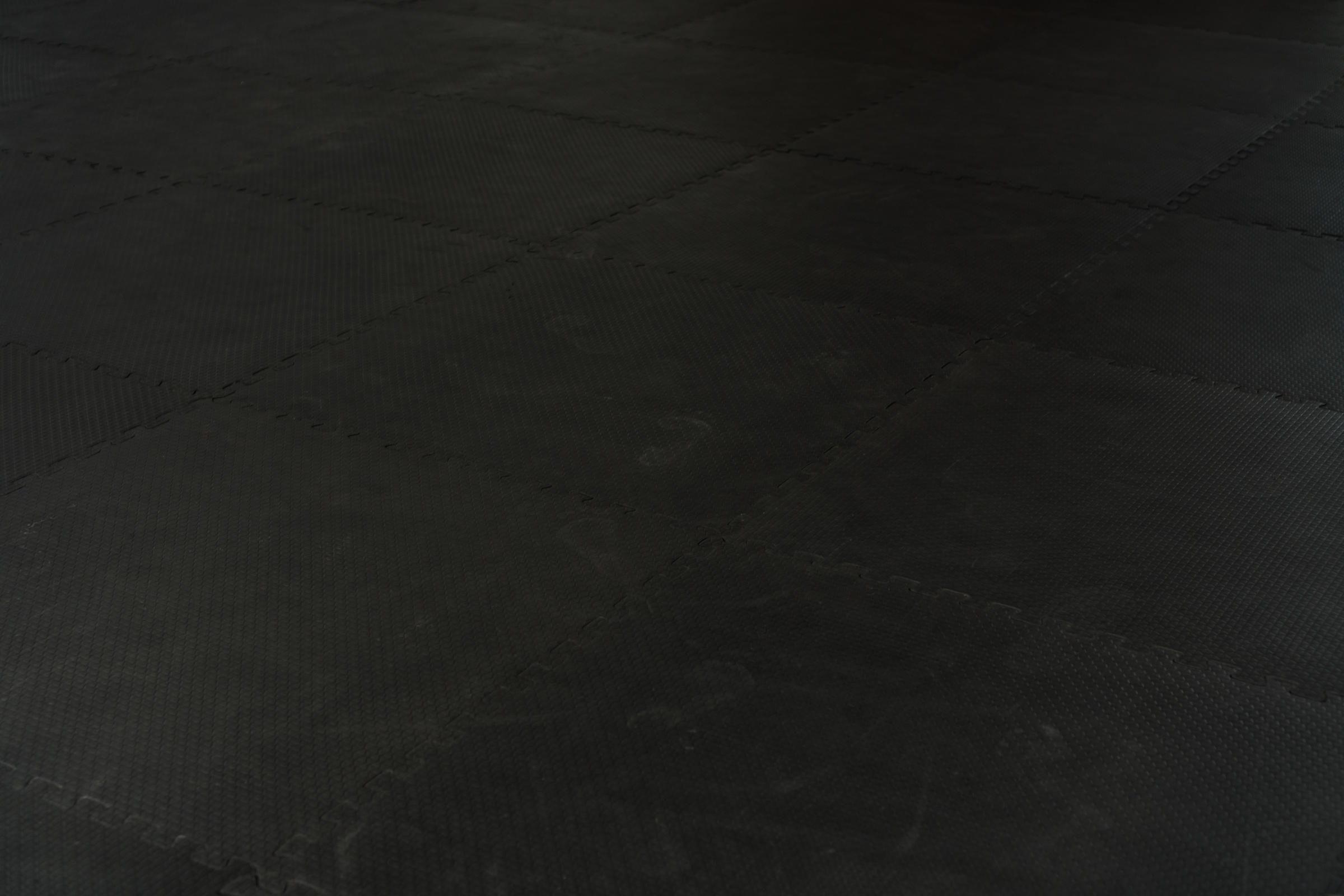 Black rubber floor mat and tiles inside a gym.